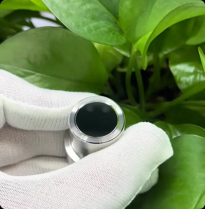 White-gloved hand holding a mirror-finish precision optical insert